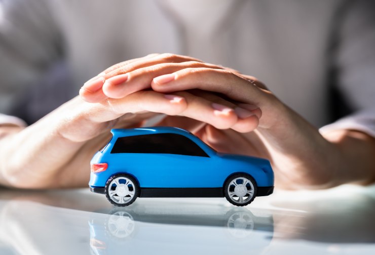 auto in miniatura sotto le mani di uomo