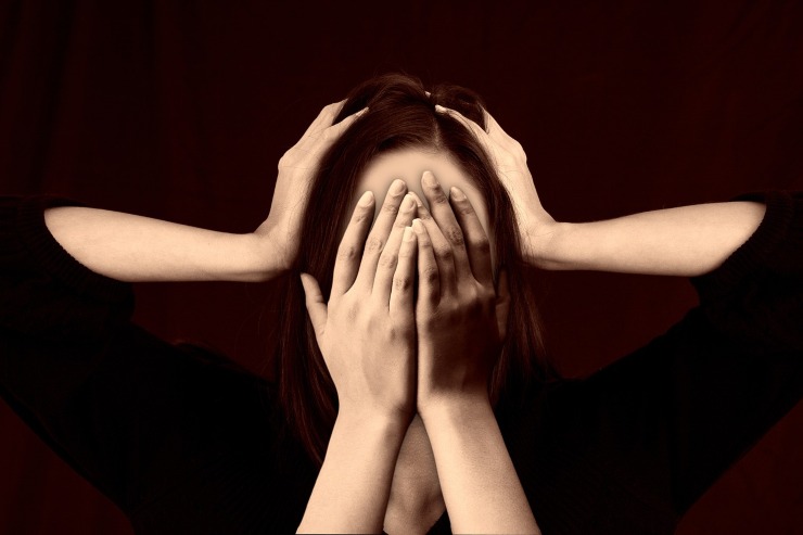 donna con le mani sul viso e due mani che le tengono le tempie