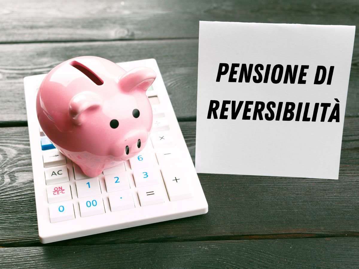 scrivania con salvadanaio, calcolatrice e biglietto con scritta pensione di reversibilità