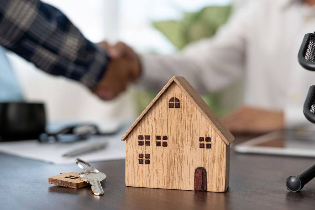 Casa in miniatura e persone che si stringono le mani dopo una compravendita