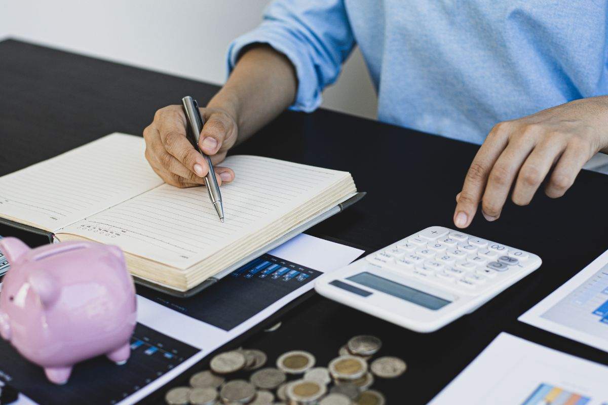Persona che fa dei calcoli per i suoi investimenti, salvadanaio e monete