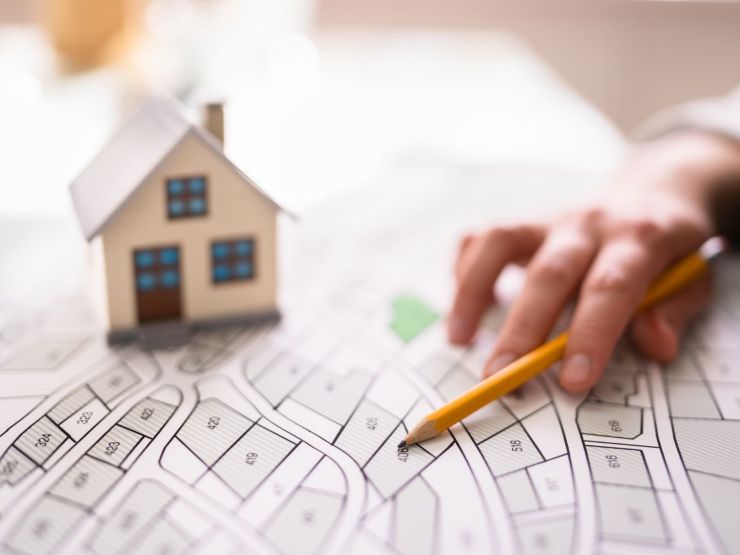 mano donna su planimetria catasto e casa in miniatura