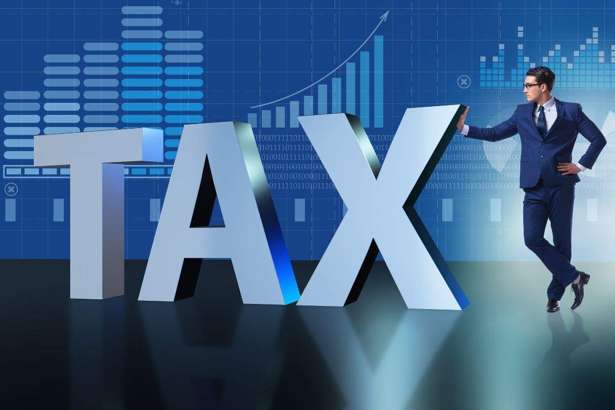 Scritta Tax sulla quale si appoggia un uomo