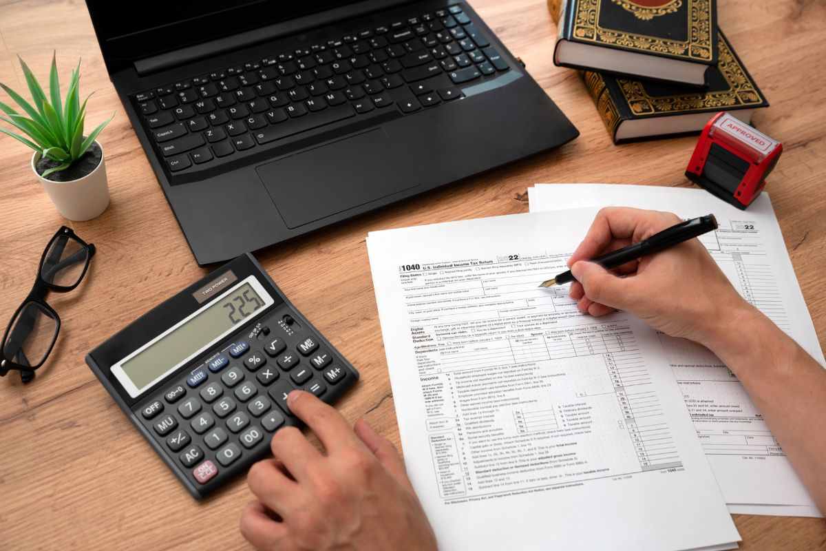 Calcolatrice, pc e persona che compila la dichiarazione dei redditi