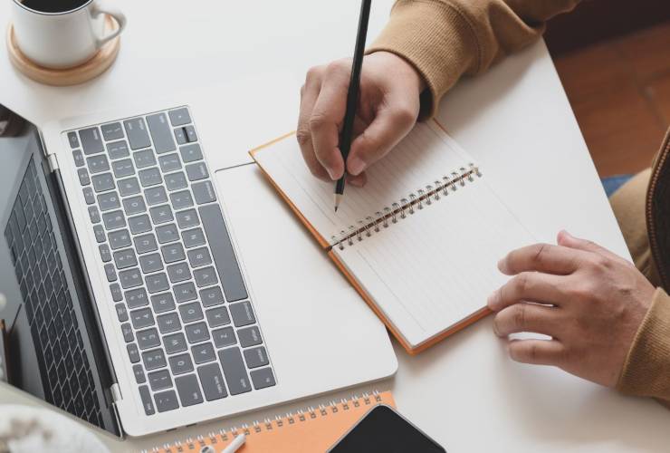 Persina che consulta il pc e prende appunti