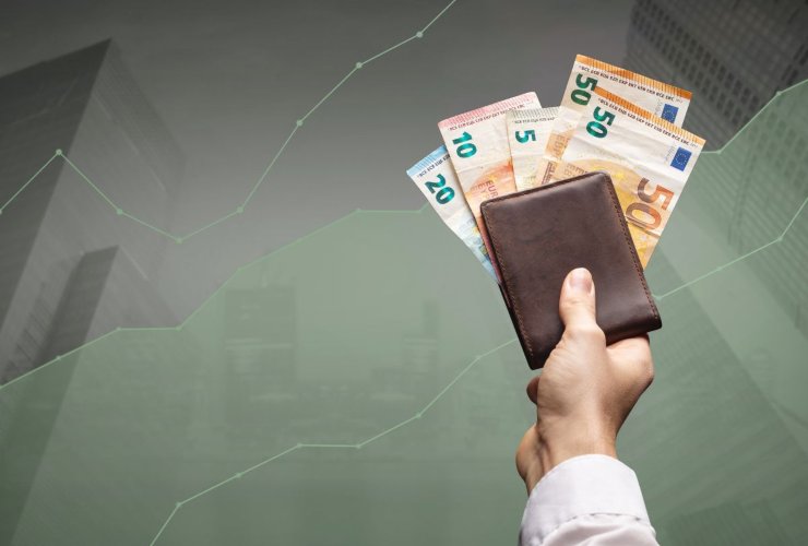 Persona che ha in mano un portafoglio dal quale scono banconote in euro