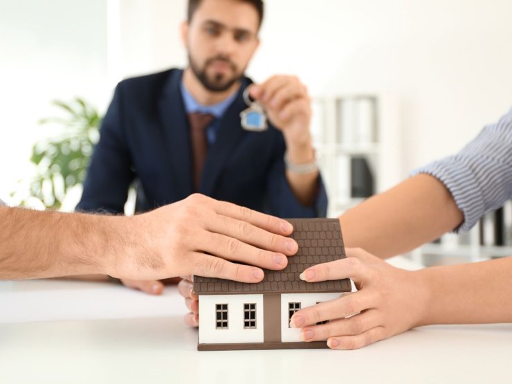 persone che stringono miniatura casa e avvocato con chiavi in mano