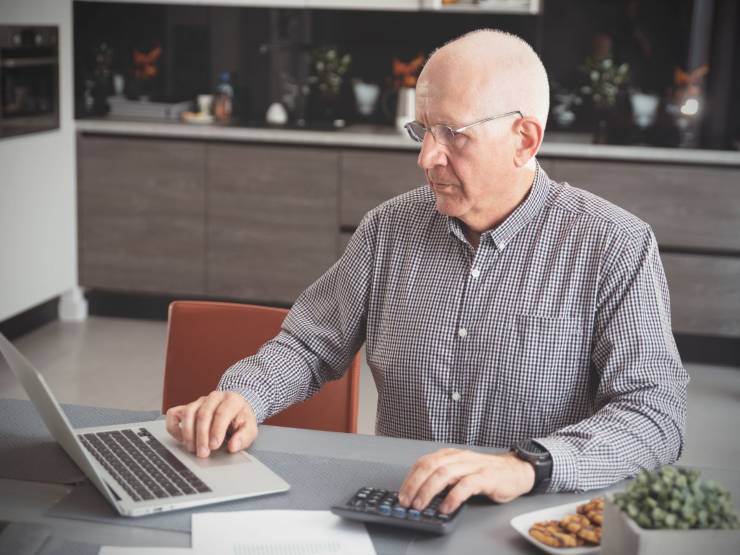 pensionato che usa il pc e la calcolatrice