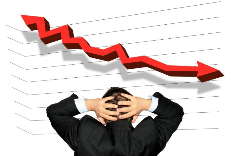 Grafico in ribasso e persona che si mette le mani in testa