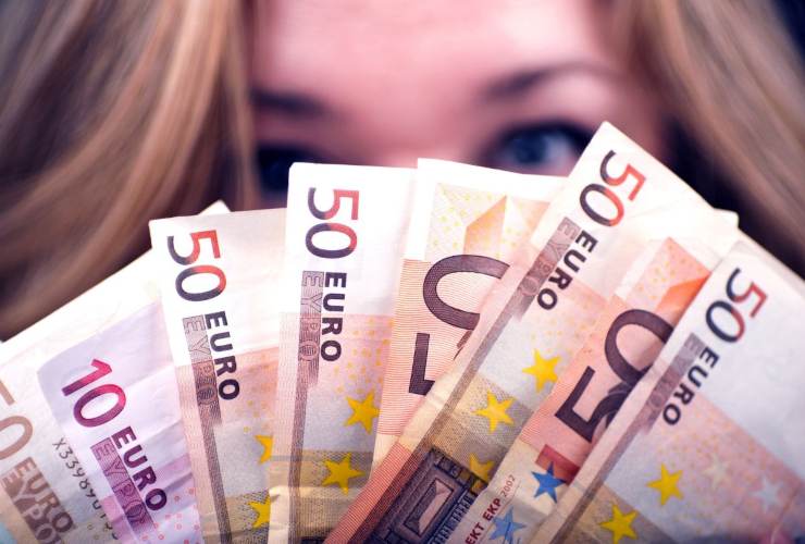Persona che si nasconde il viso dietro banconote da 50 euro
