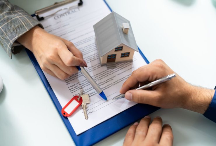 Firma di un mutuo, chiavi e miniatura di una casa
