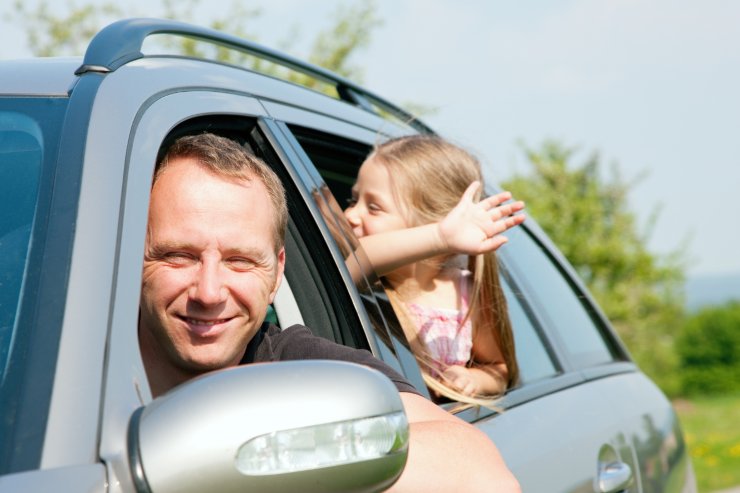 uomo e bambina che saluta in auto