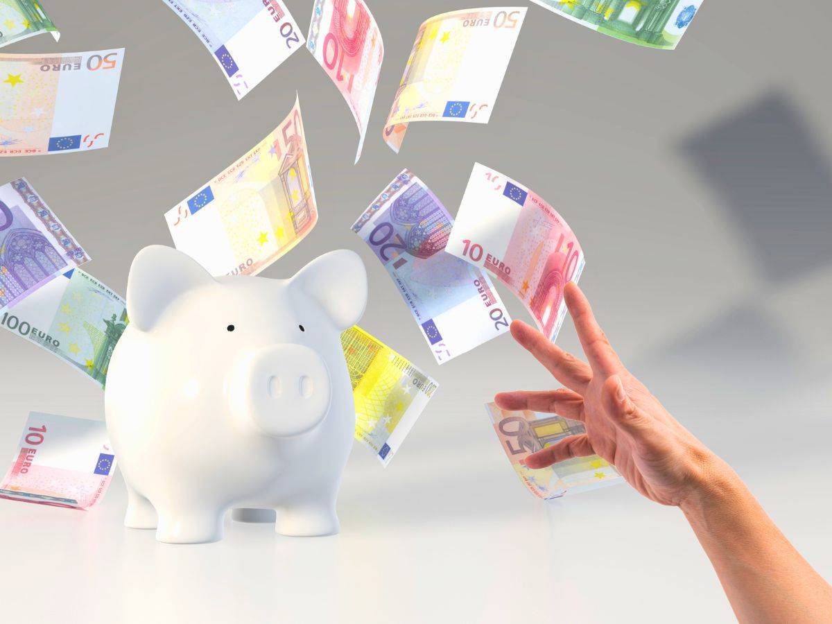 sfondo banconote euro volanti con salvadanaio e mano che tende verso di loro