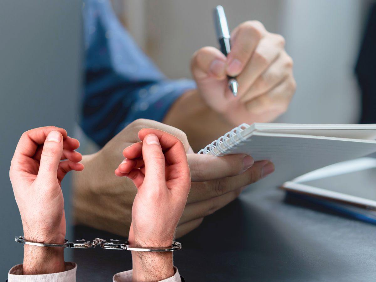 sfondo persona che scrive su quaderno e mani ammanettate