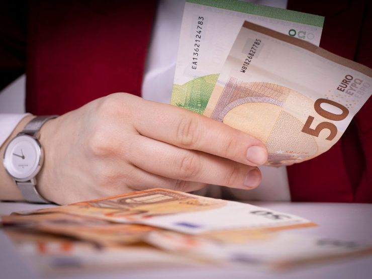persona alla scrivania con banconote euro in mano