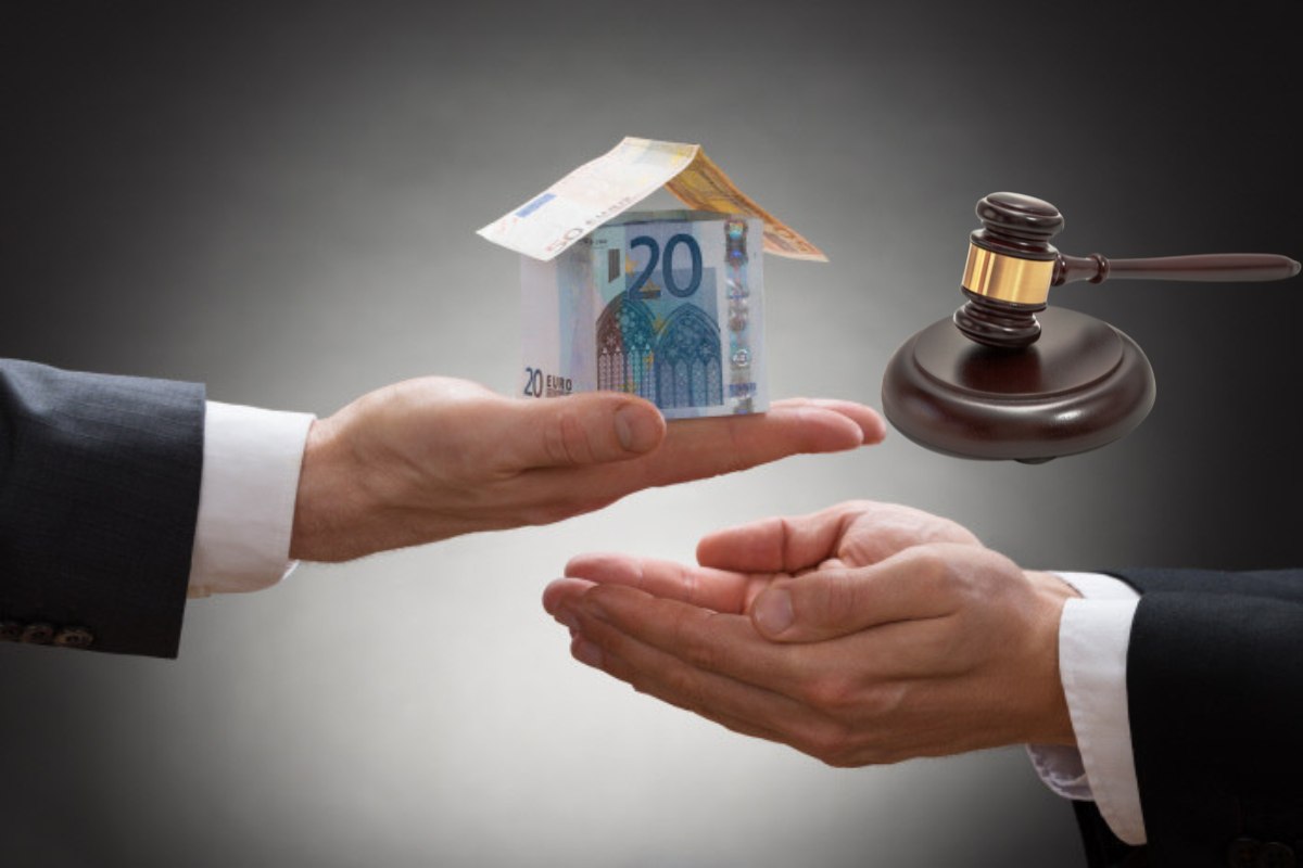 mano che consegna soldi a forma di casa ad altra mano e martelletto giudice