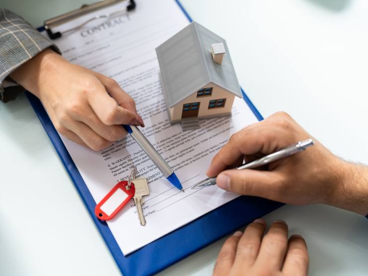 persone che controllano documento con immobile in miniatura