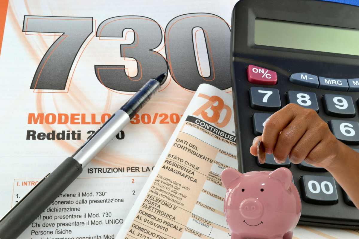730 con penna calcolatrice e mano che mette moneta nel salvadanaio