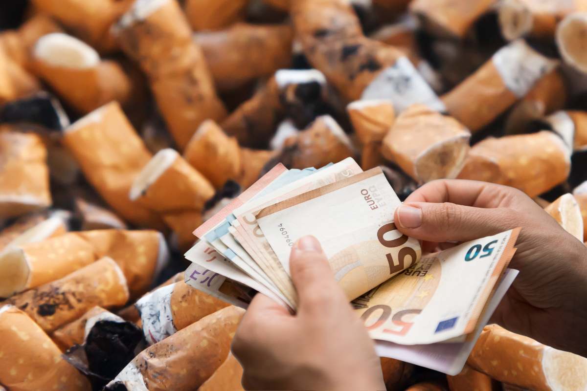 mani che contano i soldi sopra una decine di mozziconi sigaretta