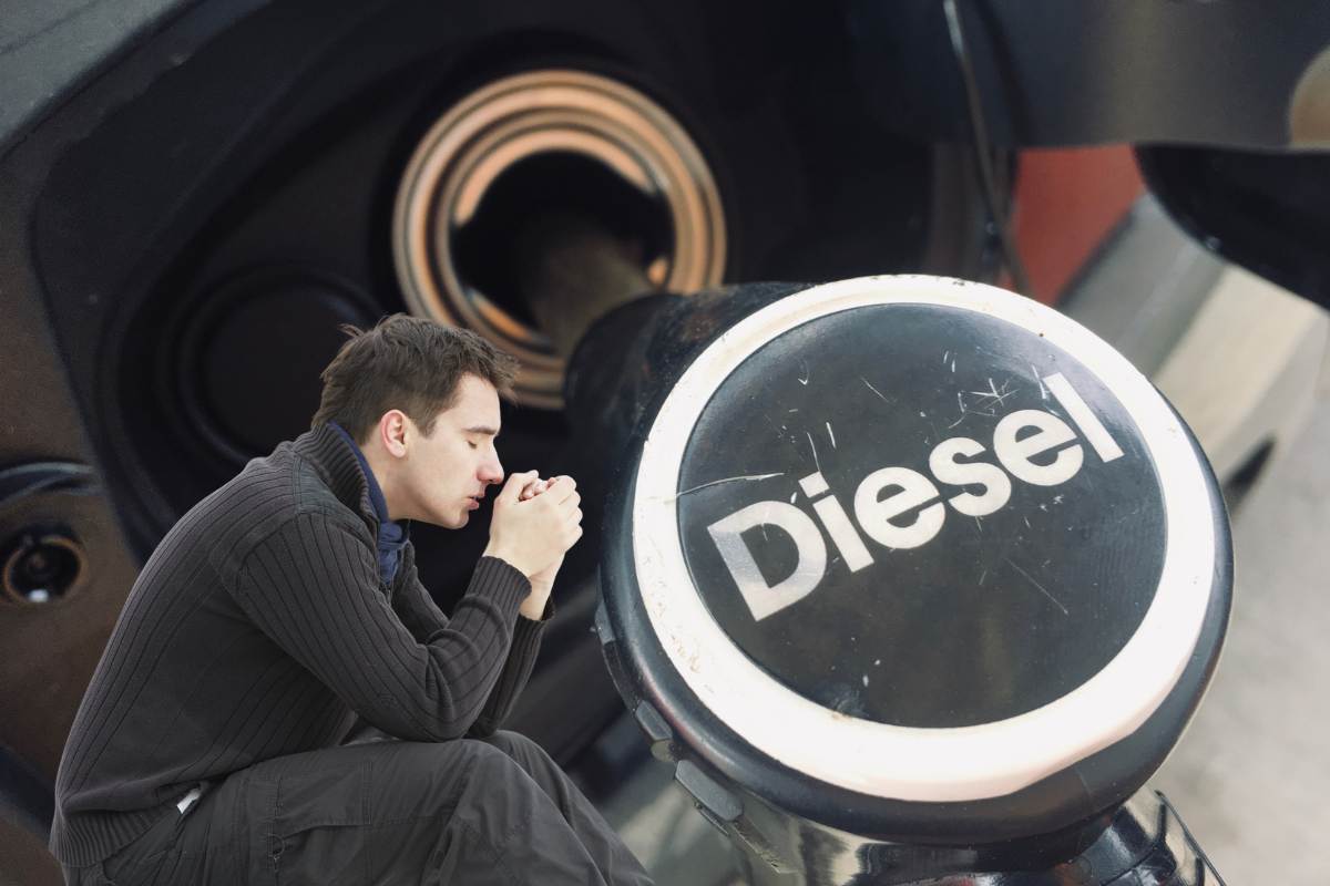 pompa diesel nel serbatoio e uomo triste seduto