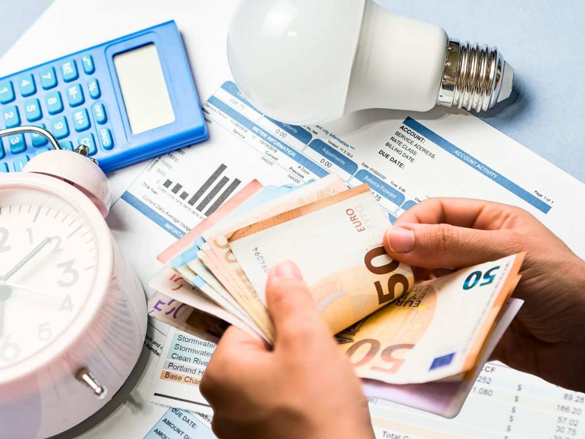 sfondo bollette, calcolatrice e lampadina e mani con banconote 50 euro