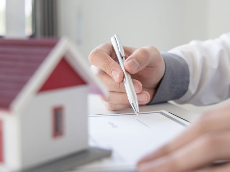 persona studia documenti e sagoma casa in miniatura