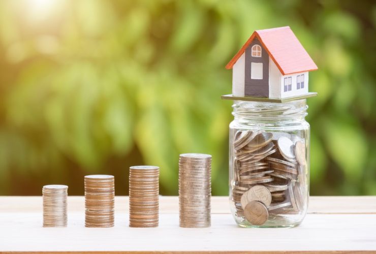 Monete, vasetto con monete e miniatura casa