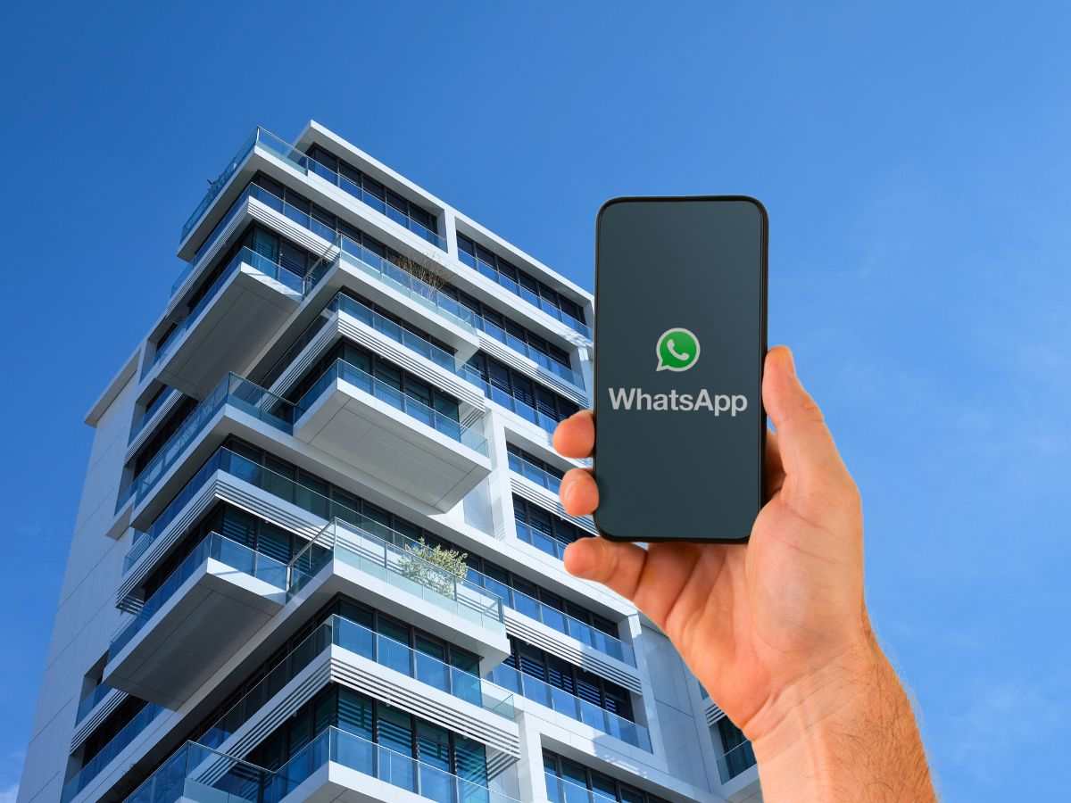 sfondo palazzo e mano con telefono con WhatsApp logo