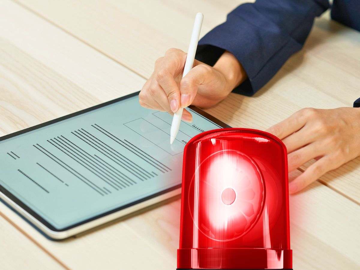 sfondo mano che firma documento in tablet e lampadina allarme accesa