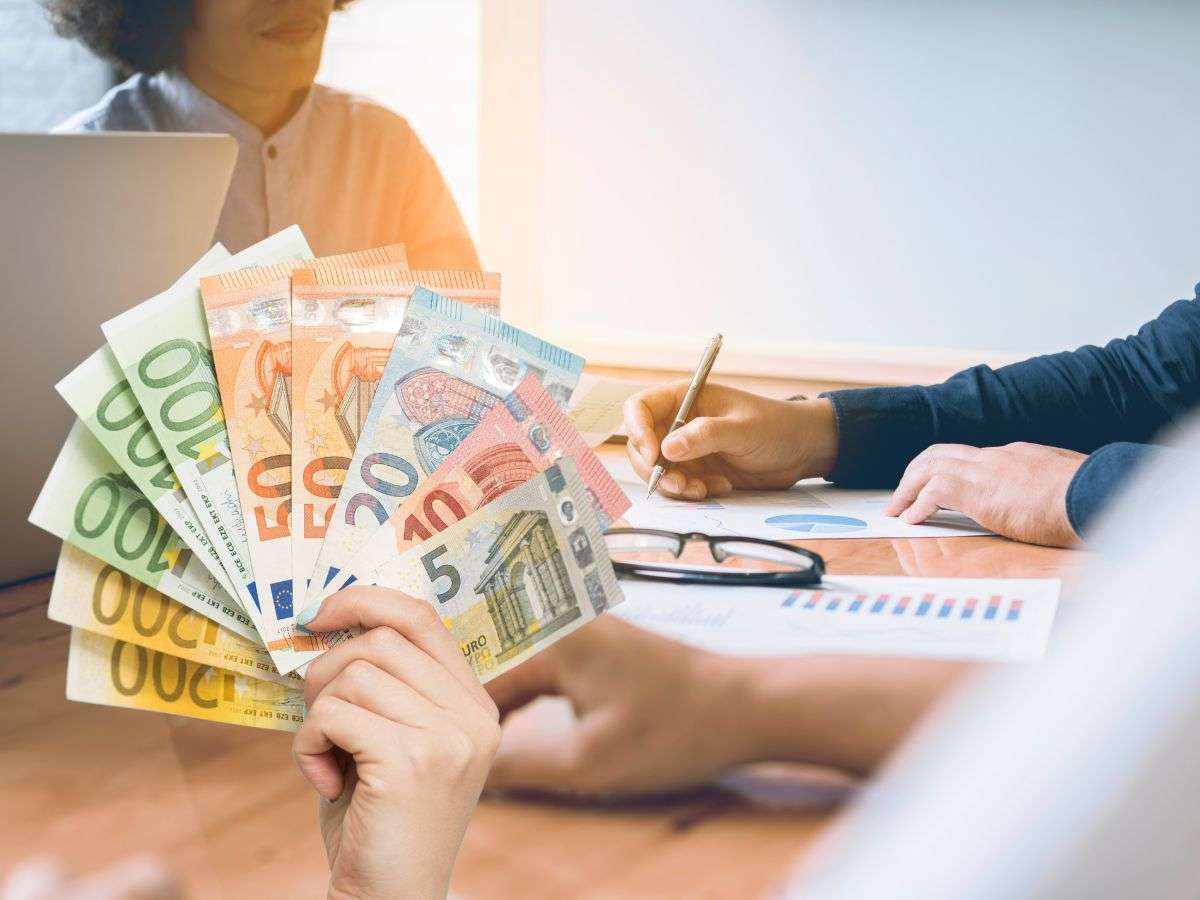 sfondo persone alla scrivania e banconote euro in mano