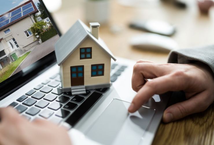 Persona che scrive al pc con miniatira casa sulla tastiera