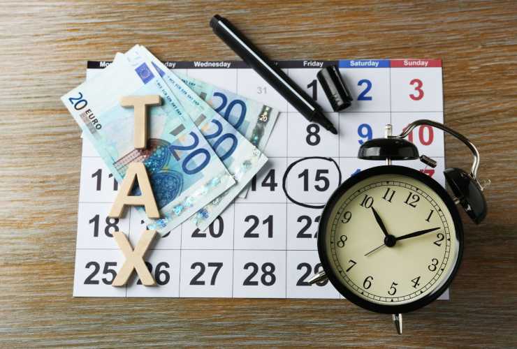 Calendario, banconote, sveglia e scritta TAX