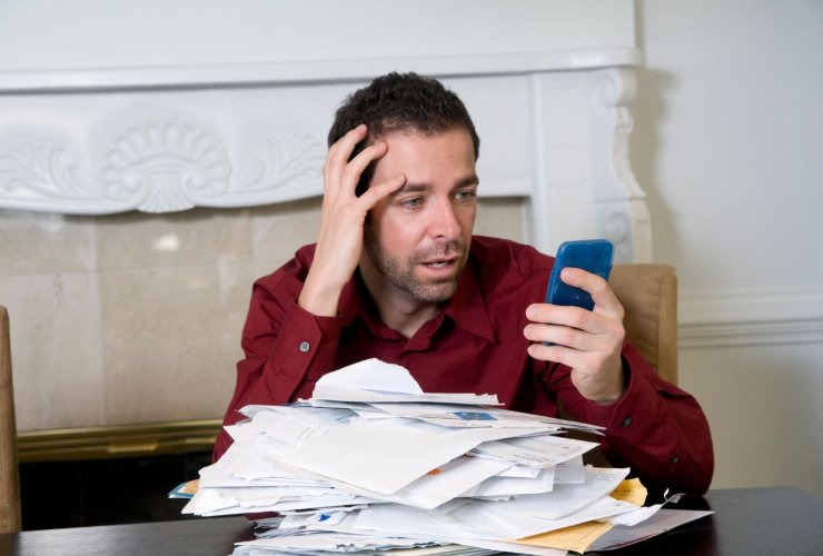 Persona oberata di debiti che guarda il cellulare