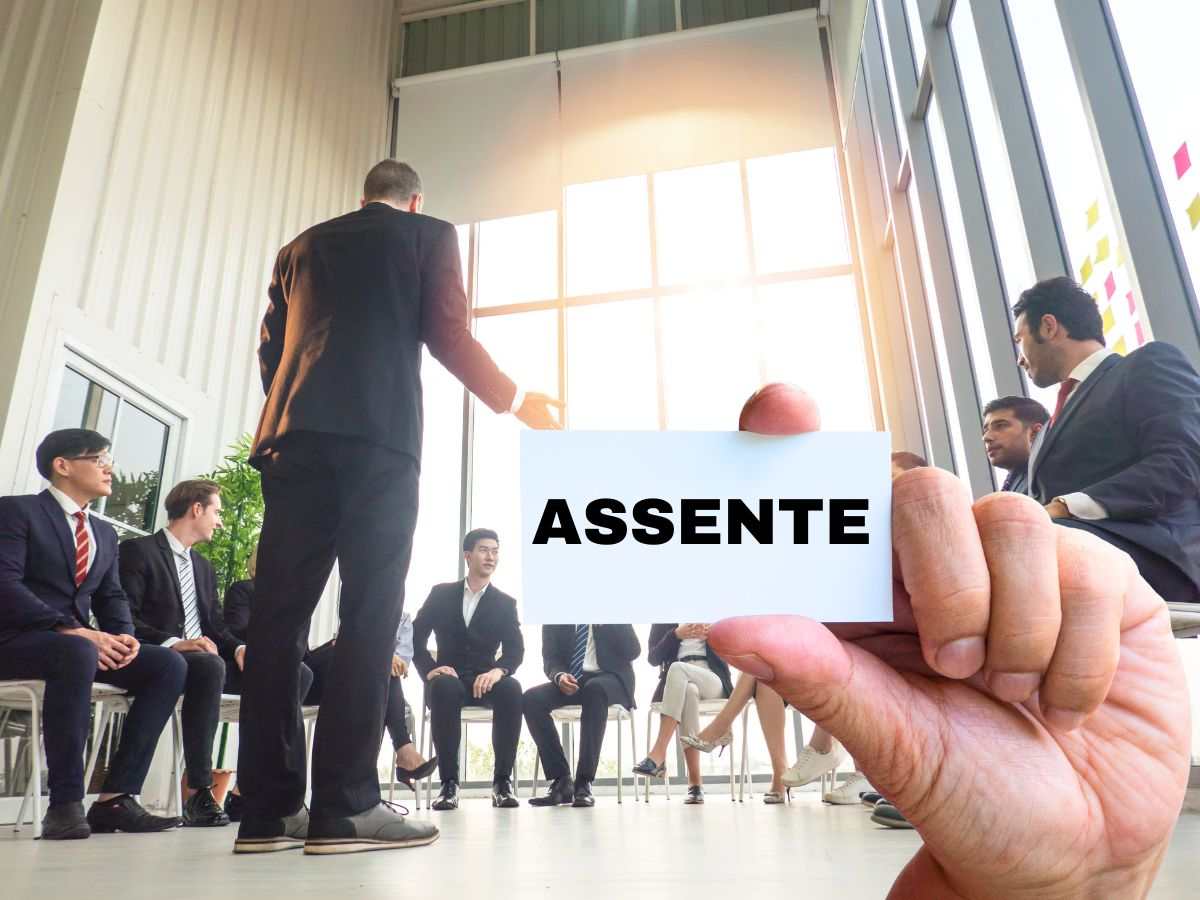 sfondo persone in assemblea e mano con cartellino con scritta assente