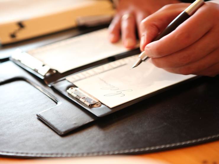 persona scrive documento a mano
