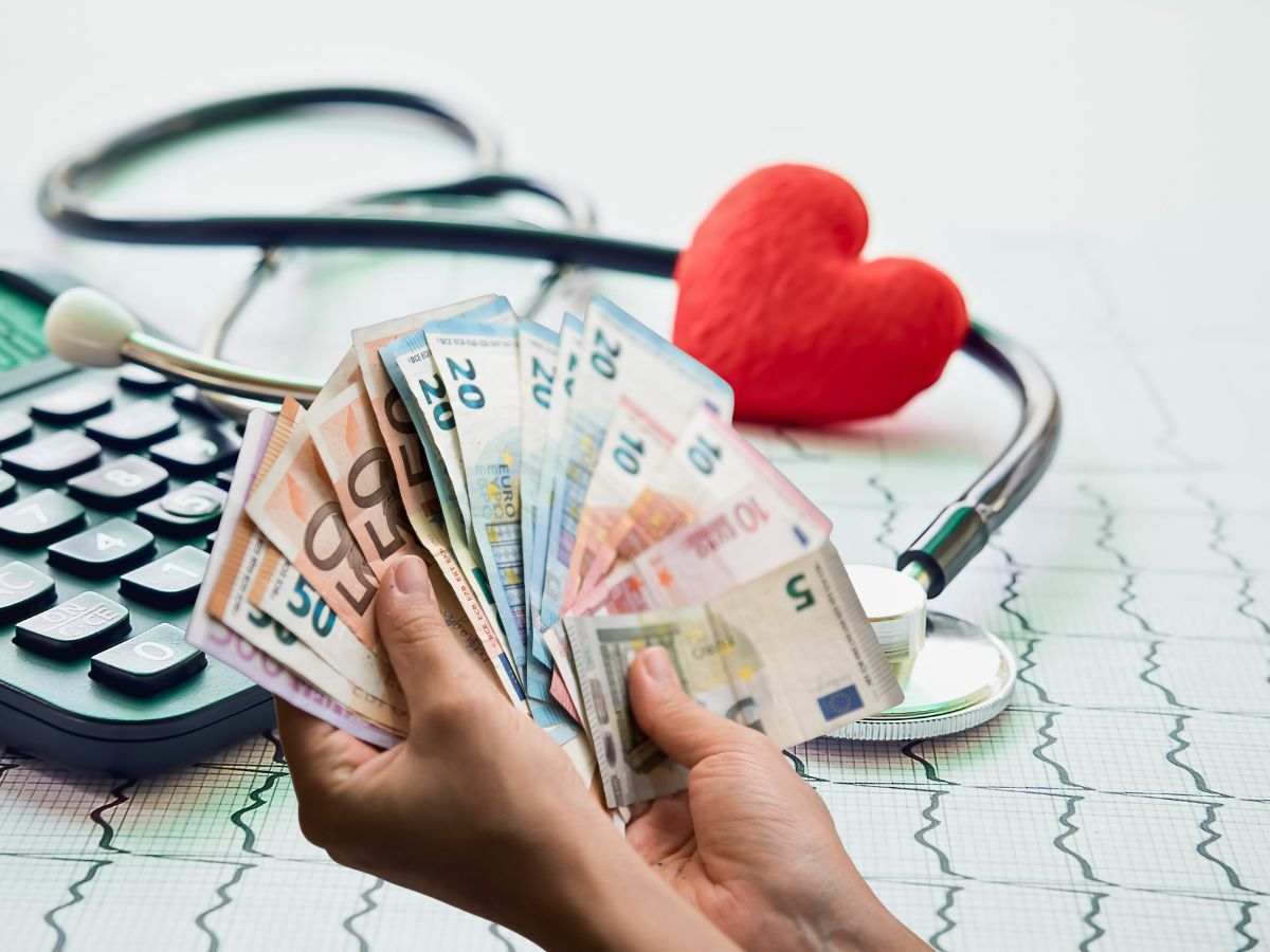 sfondo calcolatrice, cuore sagoma e stetoscopio e banconote euro in mano