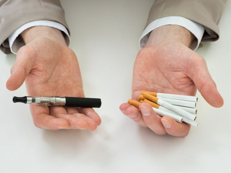 sigarette comuni e elettronica in mano