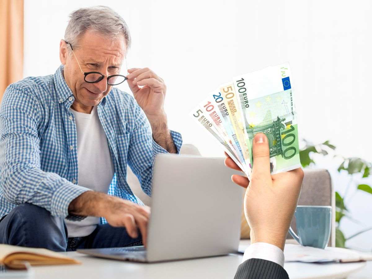 anziano al pc e mano con banconote euro