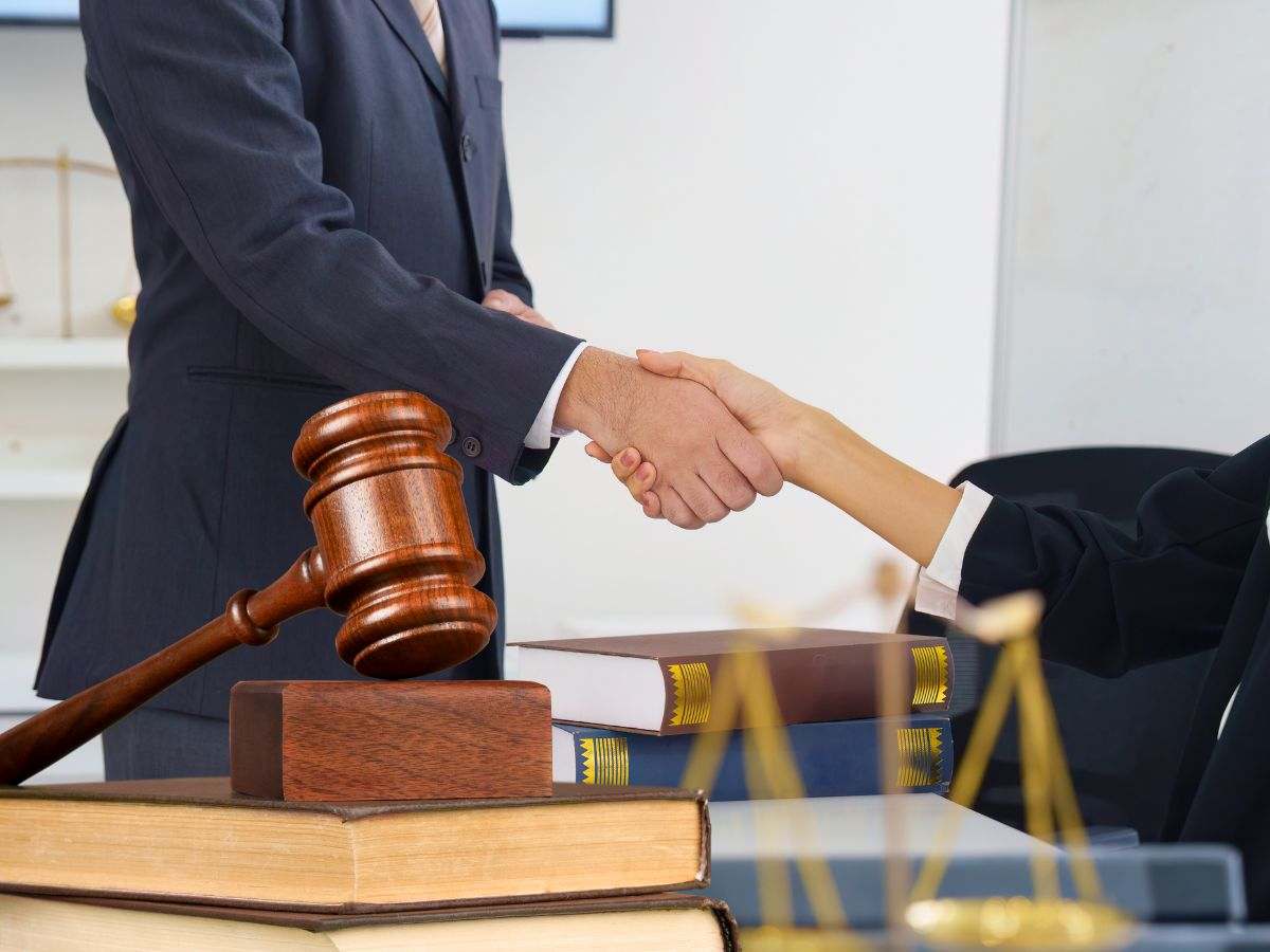 sfondo persone che si stringono la mano e libri e martelletto del giudice