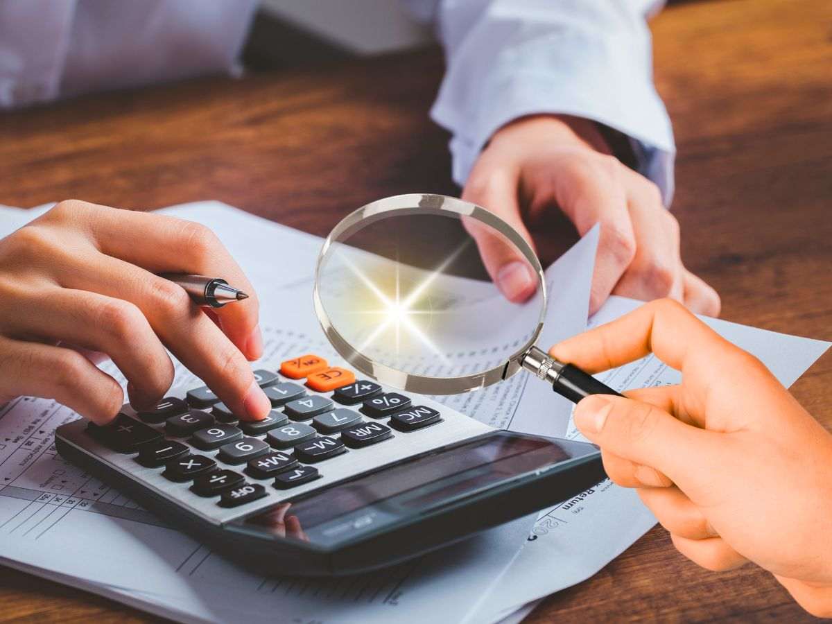sfondo persona che fa calcoli a calcolatrice e lente di ingrandimento in mano