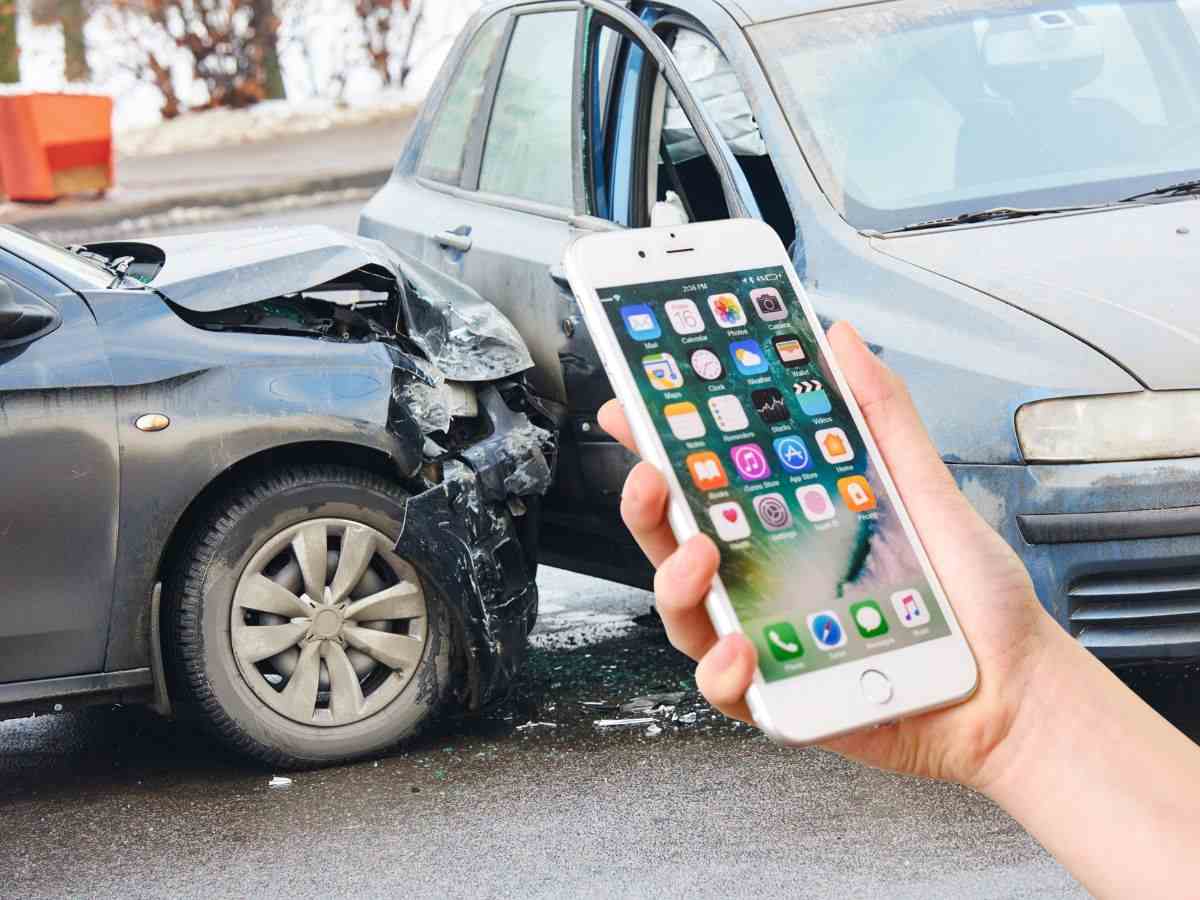 sfondo due auto in incidente e mano con smartphone