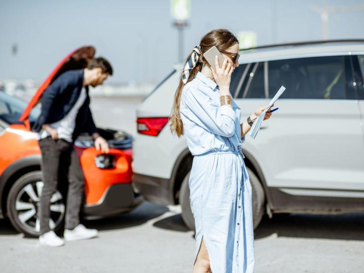 ragazza al telefono e ragazzo che controlla auto incidentate