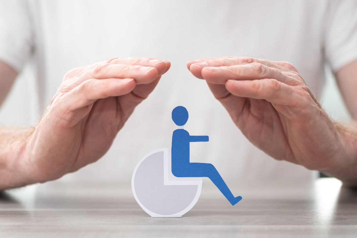 Simbolo disabilità in mezzo a due mani
