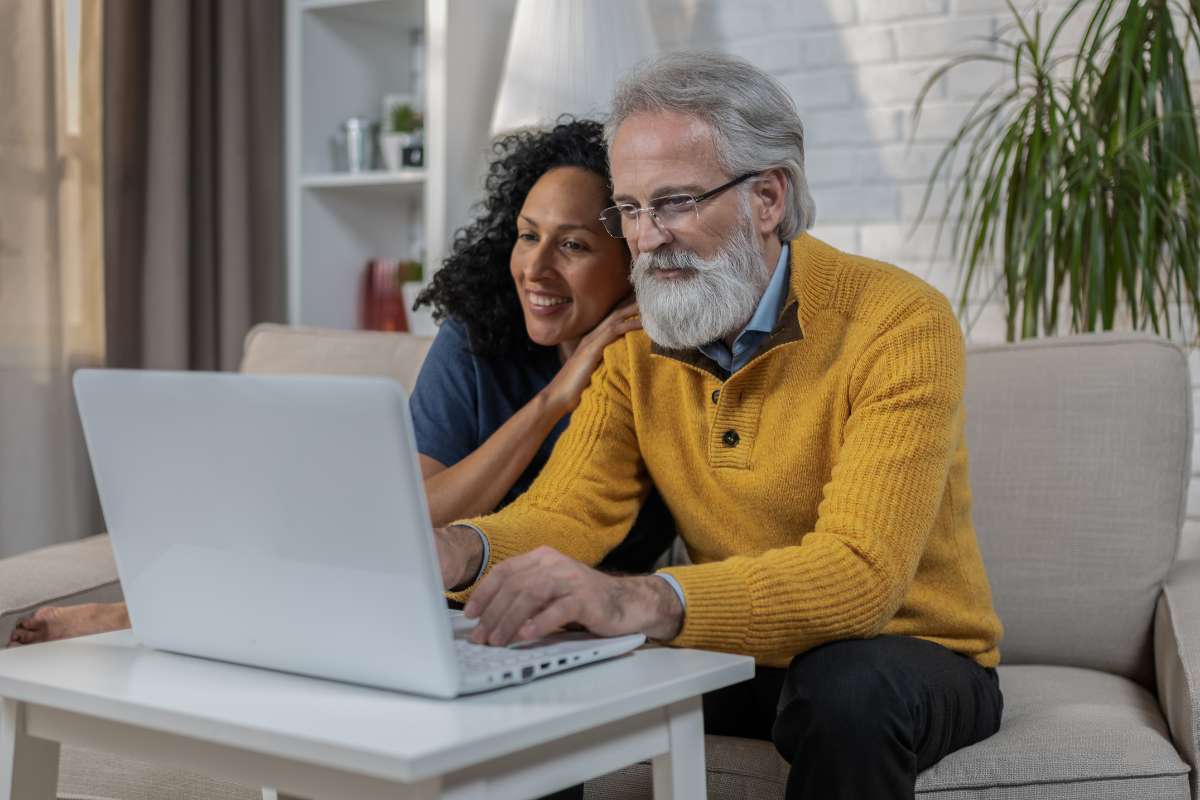 uomo e donna sorridenti di fronte a pc