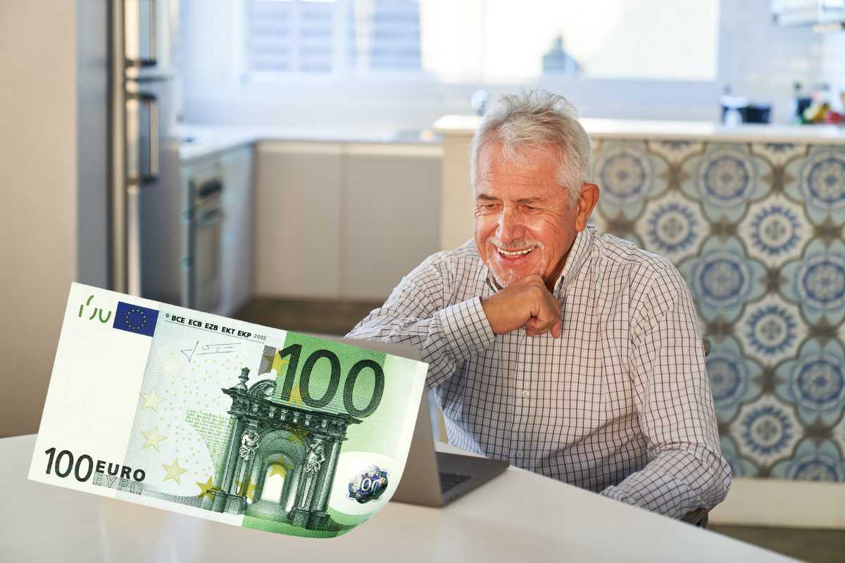 pensionato felice davanti a pc e banconota da 100 euro