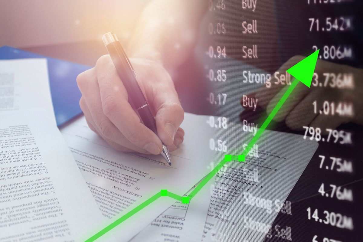 grafico azionario e persona che scrive prevsione economica