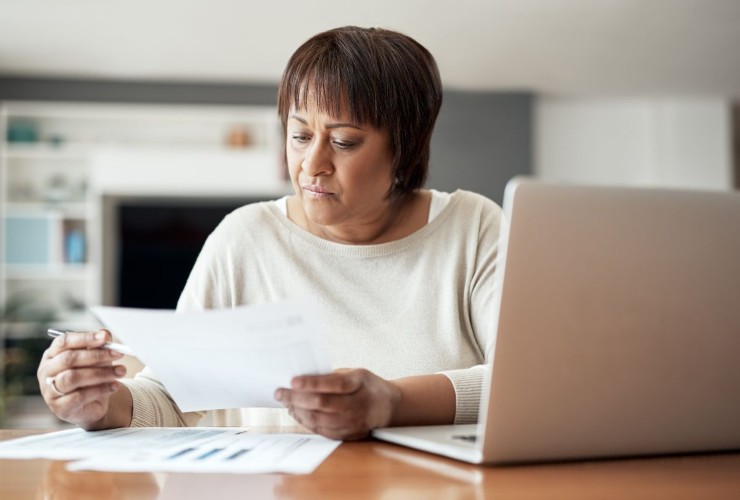 Pensionata che legge il cedolino della pensione e fa dei calcoli