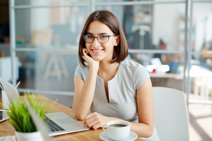 ragazza sorridente davanti a pc e tazza di caffè