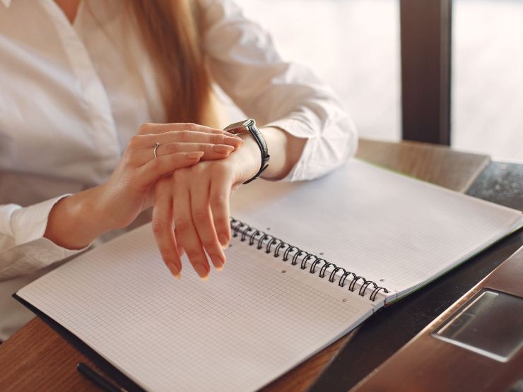 ragazza guarda orologio seduta alla scrivania
