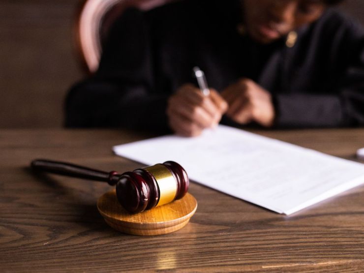 legale che scrive su scrivania e martelletto del giudice